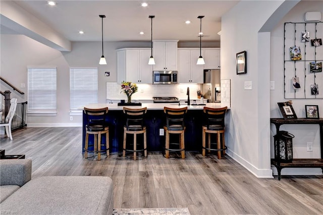 134 Fishermans Way, Poquoson, VA 23662 - kitchen with appliances with stainless steel finishes, wood finished floors, light countertops, a kitchen bar, and recessed lighting