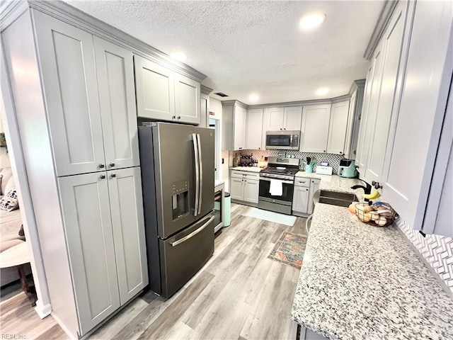 969 Westerly Trl, Virginia Beach, VA 23464 - kitchen with appliances with stainless steel finishes, decorative backsplash, light wood-style flooring, light stone counters, and a textured ceiling