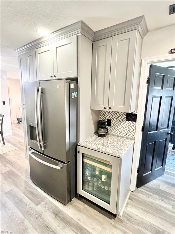 969 Westerly Trl, Virginia Beach, VA 23464 - kitchen featuring stainless steel fridge, light wood-style flooring, backsplash, light stone counters, and a textured ceiling