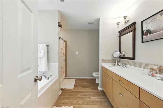 2152 Benomi Dr, Williamsburg, VA 23185 - full bath featuring vanity, wood finished floors, a shower with curtain, a relaxing tiled tub, and decorative backsplash
