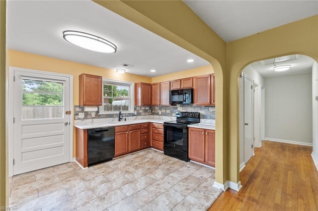 2655 Village Ave, Chesapeake, VA 23323 - kitchen with black appliances, light countertops, backsplash, arched walkways, and brown cabinets