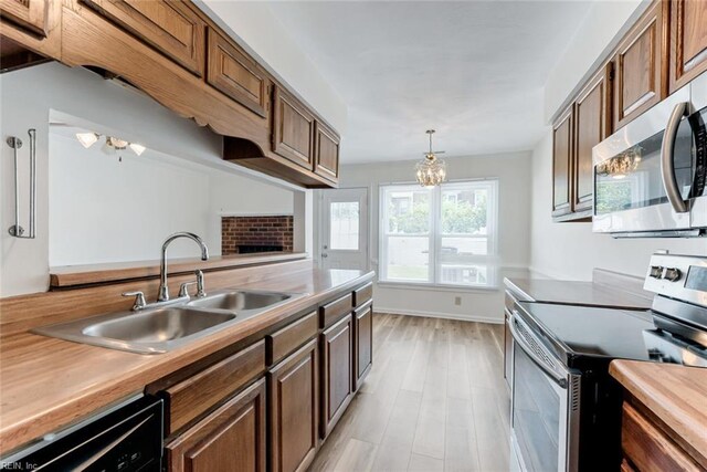 284 Windbrooke Ln, Virginia Beach, VA 23462 - kitchen featuring appliances with stainless steel finishes, a chandelier, pendant lighting, light wood-style flooring, and a brick fireplace