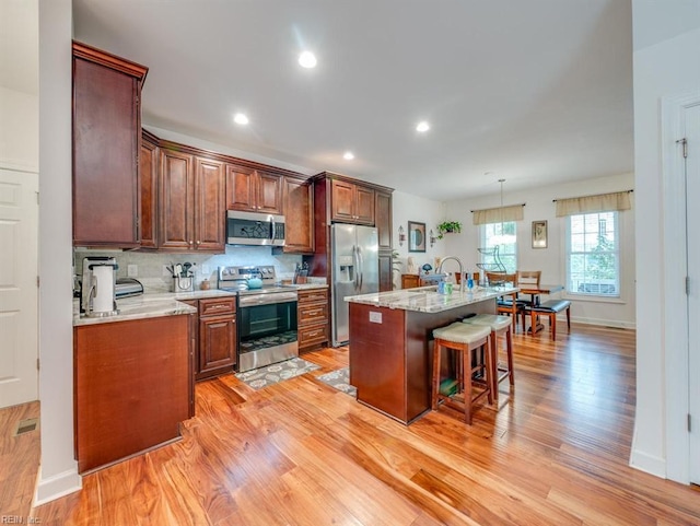 405 Oaktree Rd, Williamsburg, VA 23188 - kitchen featuring stainless steel appliances, a kitchen breakfast bar, light wood-type flooring, backsplash, and a center island with sink