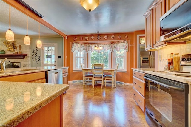 3808 Shoreline Dr, Portsmouth, VA 23703 - kitchen with stainless steel appliances, hanging light fixtures, brown cabinets, light stone counters, and backsplash