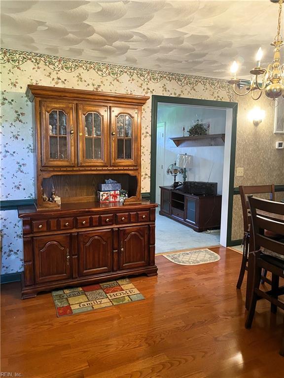 2016 Kilby Ln, Suffolk, VA 23434 - bar featuring wallpapered walls, a chandelier, wood finished floors, and hanging light fixtures