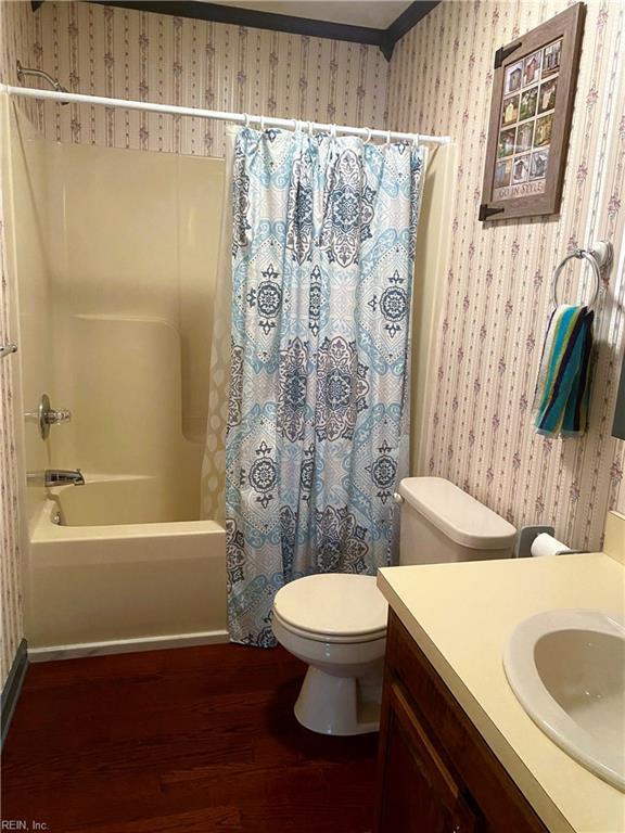 2016 Kilby Ln, Suffolk, VA 23434 - bathroom with wallpapered walls, wood finished floors, vanity, and shower / bath combo with shower curtain
