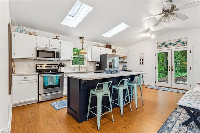 682 Bay Port Rd, Jamaica, VA 23079 - kitchen featuring appliances with stainless steel finishes, lofted ceiling, a skylight, backsplash, and white cabinetry