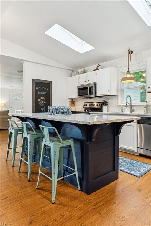 682 Bay Port Rd, Jamaica, VA 23079 - kitchen with a skylight, appliances with stainless steel finishes, white cabinetry, a breakfast bar, and vaulted ceiling