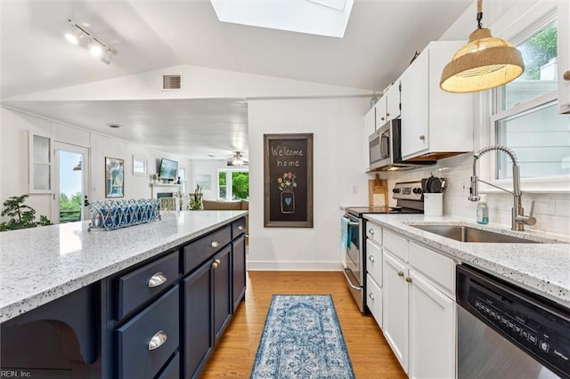 682 Bay Port Rd, Jamaica, VA 23079 - kitchen featuring appliances with stainless steel finishes, vaulted ceiling, a skylight, white cabinetry, and light wood finished floors