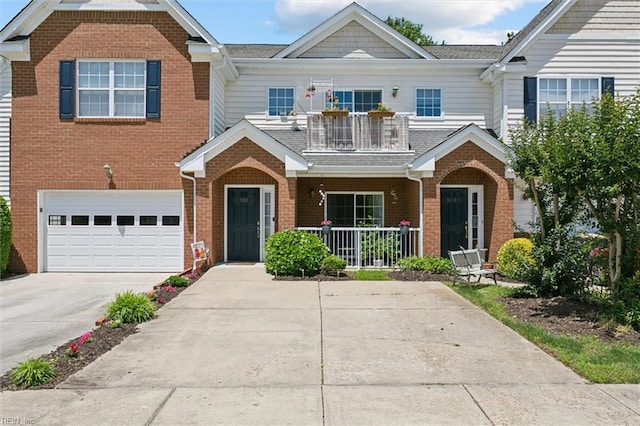 903 Rustads Cir, Williamsburg, VA 23188 - view of front of house with a balcony, concrete driveway, brick siding, a garage, and covered porch