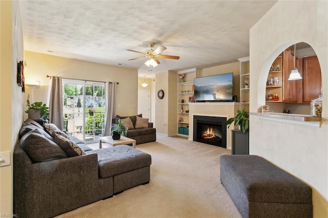 903 Rustads Cir, Williamsburg, VA 23188 - living room featuring ceiling fan, carpet, a lit fireplace, built in features, and a textured ceiling