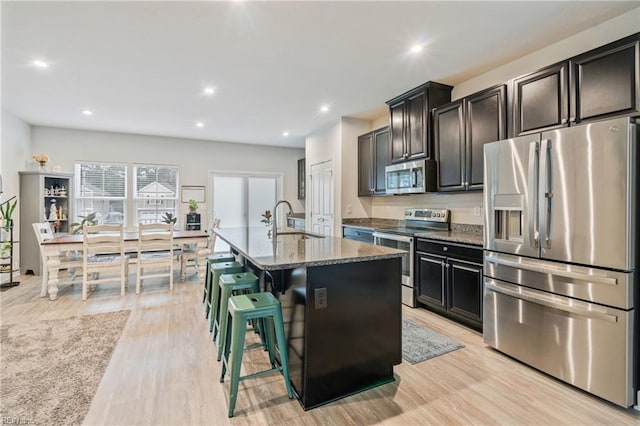 1728 Shorebird Ln, Virginia Beach, VA 23456 - kitchen with appliances with stainless steel finishes, dark stone countertops, light wood-style flooring, a kitchen island with sink, and recessed lighting