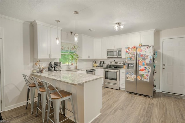 2028 Hickorywood Dr, Suffolk, VA 23434 - kitchen with stainless steel appliances, a peninsula, a textured ceiling, light wood-style floors, and white cabinets