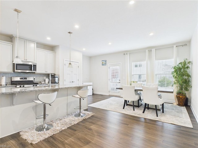 1732 Defiance Dr, Chesapeake, VA 23323 - kitchen featuring appliances with stainless steel finishes, a kitchen bar, tasteful backsplash, light stone countertops, and recessed lighting