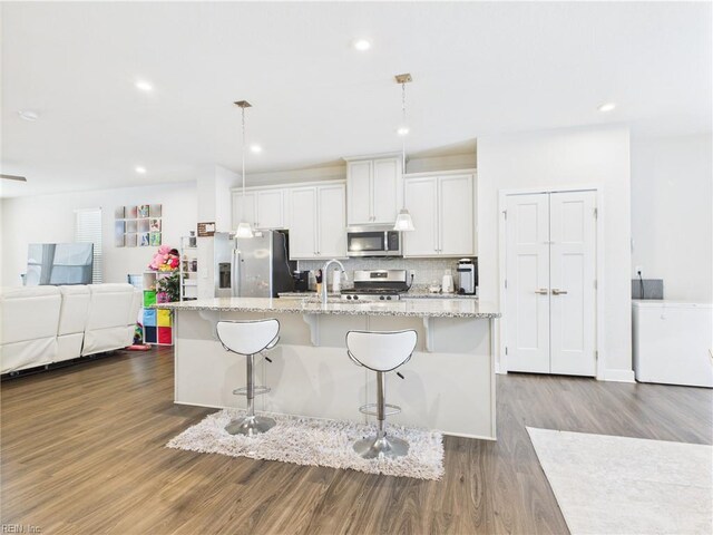 1732 Defiance Dr, Chesapeake, VA 23323 - kitchen with stainless steel appliances, dark wood finished floors, a kitchen island with sink, a kitchen breakfast bar, and decorative backsplash