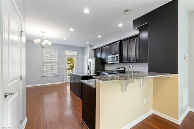 4371 Pickney Ln, Chesapeake, VA 23324 - kitchen featuring appliances with stainless steel finishes, a kitchen bar, dark wood-type flooring, a center island, and stone countertops