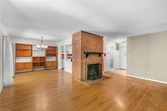 518 Spring Trce, Williamsburg, VA 23188 - unfurnished living room featuring a brick fireplace, light wood-style floors, and a chandelier