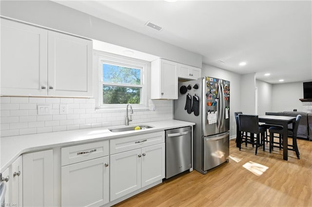 1217 Etworth Ln, Virginia Beach, VA 23464 - kitchen with stainless steel appliances, light wood-type flooring, white cabinetry, tasteful backsplash, and light countertops