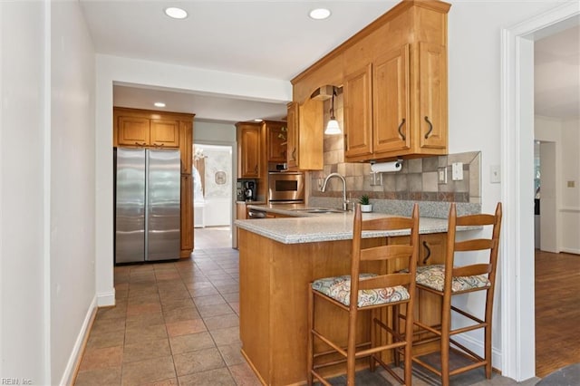 11 Elm Ave, Newport News, VA 23601 - kitchen with stainless steel appliances, decorative backsplash, recessed lighting, a peninsula, and brown cabinets