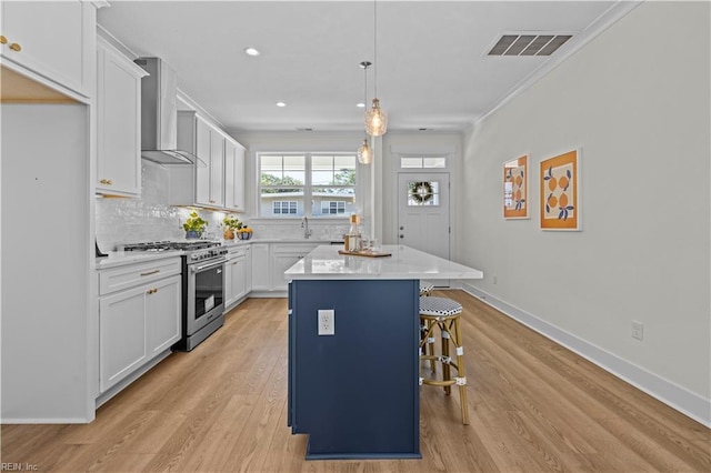 516 26th St, Virginia Beach, VA 23451 - kitchen featuring wall chimney range hood, stainless steel range, ornamental molding, a center island, and a kitchen bar