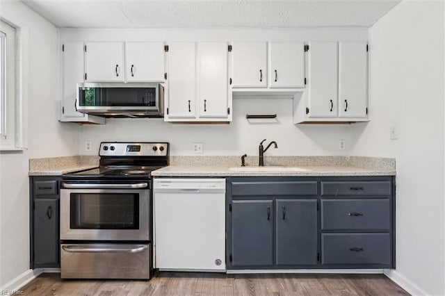 1521 Peabody Dr, Hampton, VA 23666 - kitchen with stainless steel appliances, white cabinetry, wood finished floors, and light countertops