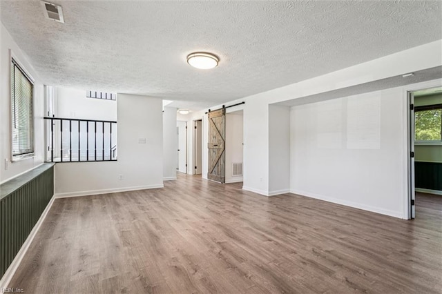 1521 Peabody Dr, Hampton, VA 23666 - spare room featuring a barn door, wood finished floors, and a textured ceiling