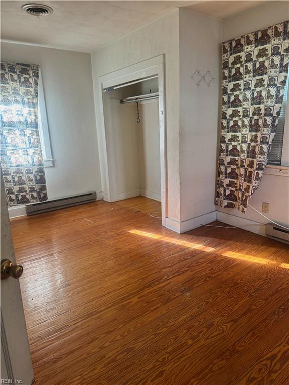 1300 Cass St, Norfolk, VA 23523 - unfurnished bedroom featuring wood finished floors and a baseboard heating unit