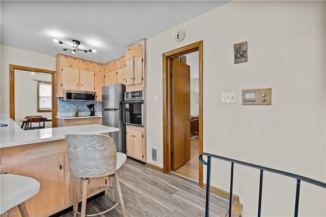 2218 Haywood Ave, Chesapeake, VA 23324 - kitchen featuring stainless steel appliances, light brown cabinetry, light wood finished floors, light countertops, and backsplash
