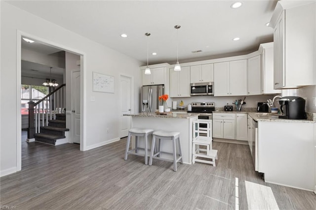 208 Parkdale Ave, Hampton, VA 23669 - kitchen with appliances with stainless steel finishes, a kitchen island, light wood-style flooring, white cabinetry, and a breakfast bar area