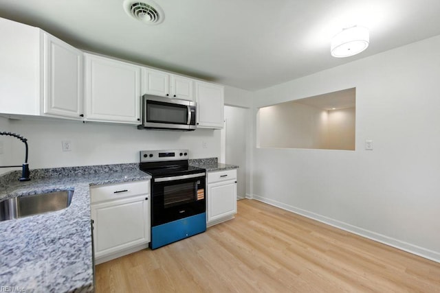 3144 Aaron Dr, Chesapeake, VA 23323 - kitchen with stainless steel microwave, black electric range oven, light wood finished floors, and white cabinets