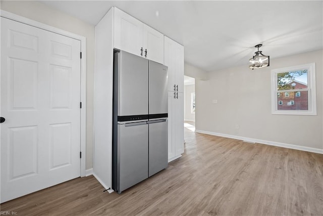10 Church St, Windsor, VA 23487 - kitchen with freestanding refrigerator, light wood-style flooring, white cabinetry, a chandelier, and decorative light fixtures