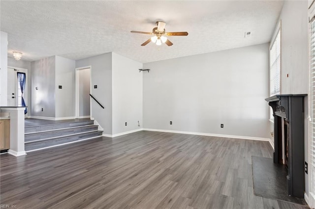 100 Peacepipe Pl, Williamsburg, VA 23185 - unfurnished living room featuring ceiling fan, dark wood-style floors, a fireplace with raised hearth, stairway, and a textured ceiling
