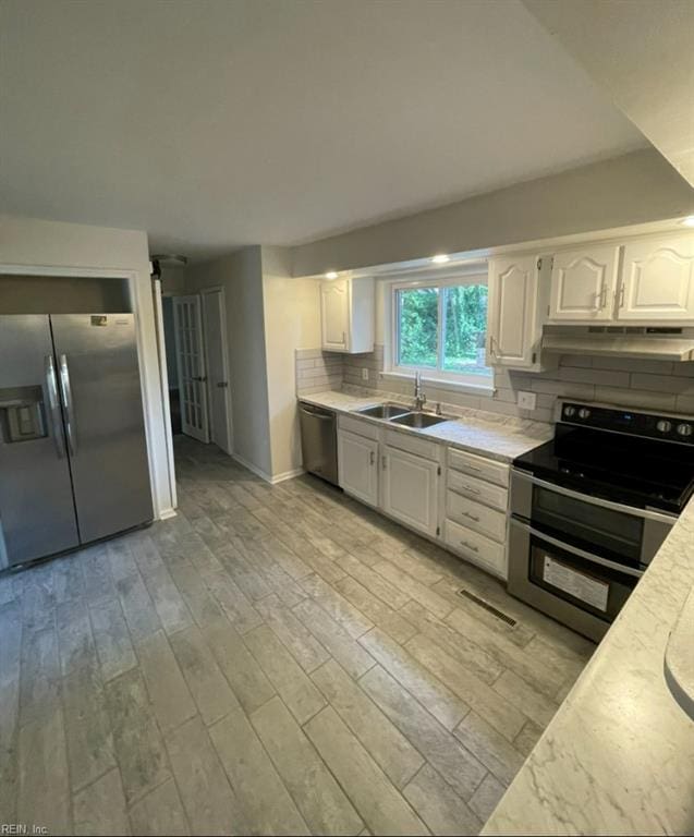 2932 Sunrise Ave, Chesapeake, VA 23324 - kitchen with stainless steel appliances, under cabinet range hood, light countertops, tasteful backsplash, and white cabinetry