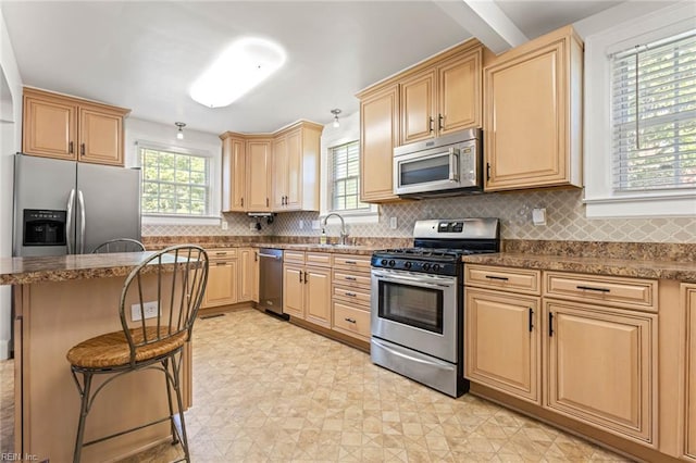 414 Russell St, Portsmouth, VA 23707 - kitchen with appliances with stainless steel finishes, a breakfast bar, light brown cabinets, backsplash, and a kitchen island