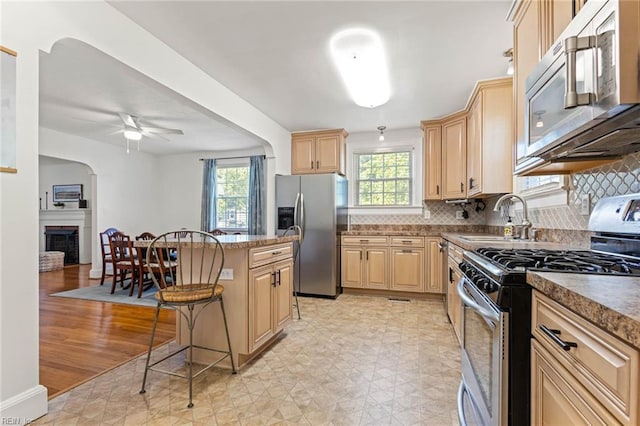 414 Russell St, Portsmouth, VA 23707 - kitchen featuring appliances with stainless steel finishes, light brown cabinetry, a breakfast bar area, ceiling fan, and tasteful backsplash