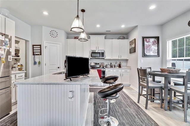 145 Blessing Cir, Suffolk, VA 23434 - kitchen with stainless steel appliances, light wood finished floors, white cabinets, recessed lighting, and an island with sink