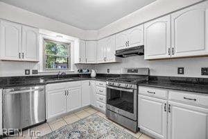 1879 Eastborne Dr, Virginia Beach, VA 23454 - kitchen with appliances with stainless steel finishes, exhaust hood, dark countertops, white cabinetry, and light tile patterned flooring