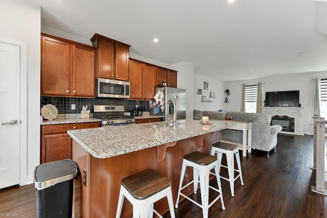 1803 Yardarm Way, Chesapeake, VA 23323 - kitchen featuring stainless steel appliances, dark wood-style flooring, decorative backsplash, brown cabinets, and a center island with sink