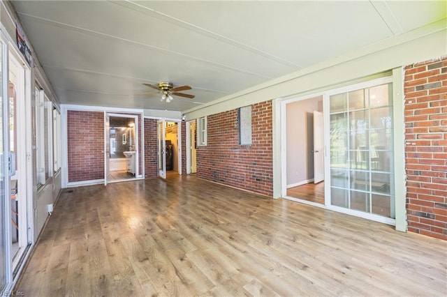 556 Summers Dr, Norfolk, VA 23509 - unfurnished sunroom with wood finished floors, brick wall, a ceiling fan, and a deck