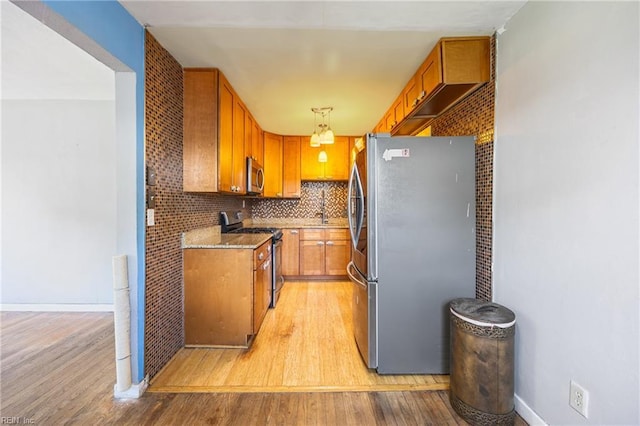 556 Summers Dr, Norfolk, VA 23509 - kitchen with appliances with stainless steel finishes, light wood-type flooring, brown cabinetry, and pendant lighting