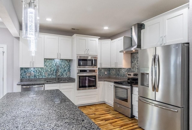 1161 Bells Mill Rd, Chesapeake, VA 23322 - kitchen with appliances with stainless steel finishes, wall chimney exhaust hood, white cabinetry, light wood-type flooring, and recessed lighting
