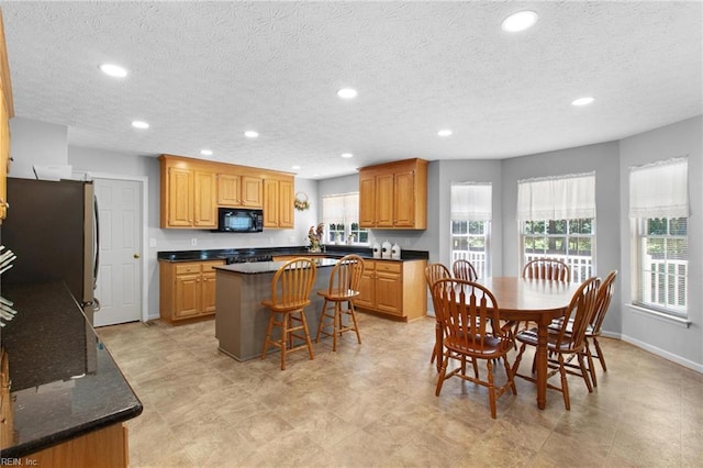 203 Vixen Ct, Yorktown, VA 23693 - kitchen with black microwave, a center island, freestanding refrigerator, recessed lighting, and a breakfast bar area