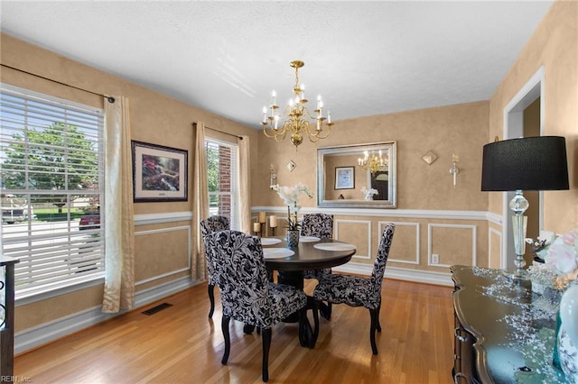 203 Vixen Ct, Yorktown, VA 23693 - dining space featuring a chandelier, wood finished floors, a wainscoted wall, and a decorative wall