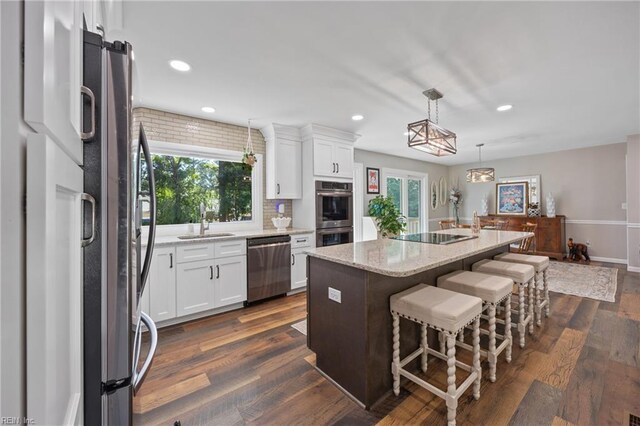 205 Ridgeland Dr, Smithfield, VA 23430 - kitchen featuring appliances with stainless steel finishes, white cabinets, a center island, light stone counters, and recessed lighting