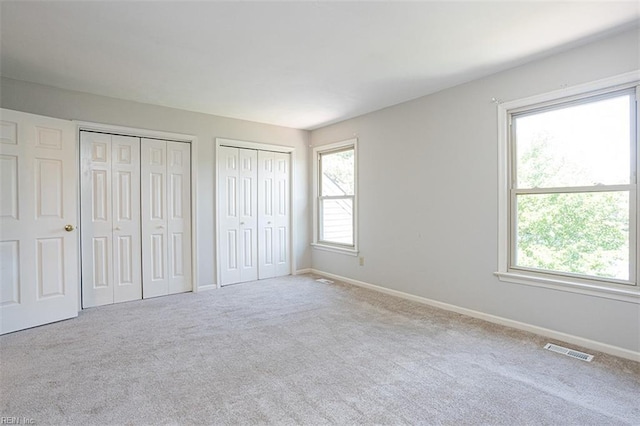 751 S Lake Cir, Chesapeake, VA 23322 - unfurnished bedroom with two closets, multiple windows, and carpet flooring