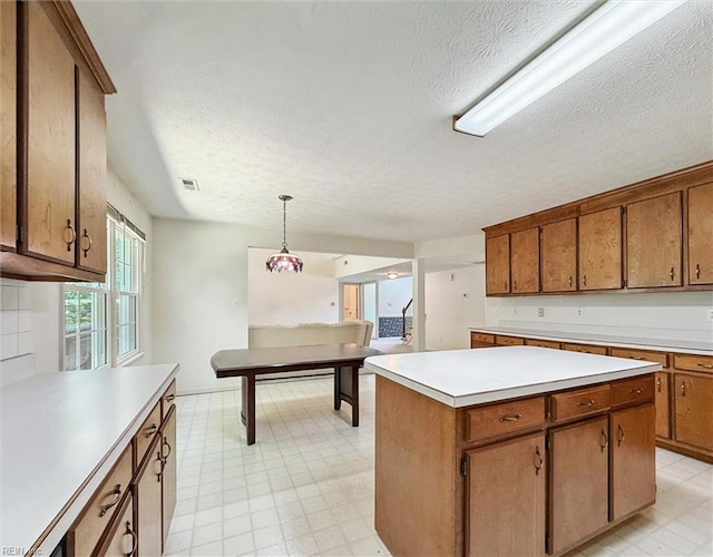 104 Hounds Chase Chase, Yorktown, VA 23693 - kitchen with light flooring, a textured ceiling, light countertops, a center island, and decorative light fixtures