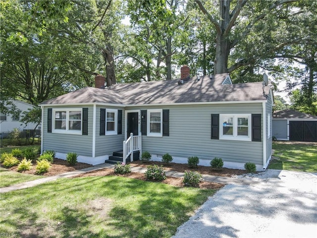 704 73rd St, Newport News, VA 23605 - view of front of property featuring a front lawn, a chimney, roof with shingles, and an outbuilding