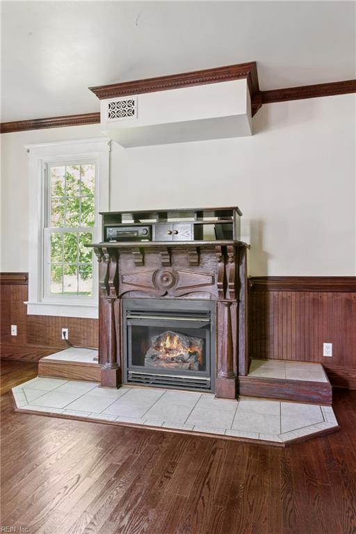 515 Beach Rd, Hampton, VA 23664 - detailed view of wainscoting, crown molding, wood finished floors, a glass covered fireplace, and wood walls