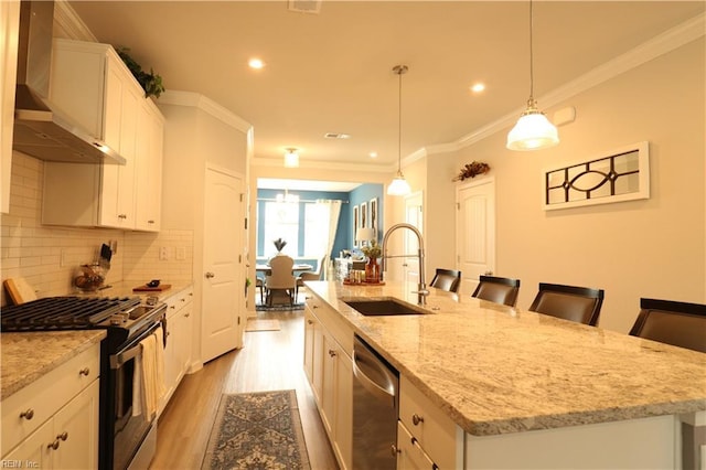 1815 Honey Milk Rd, Chesapeake, VA 23323 - kitchen featuring appliances with stainless steel finishes, wall chimney range hood, a kitchen island with sink, light wood-style floors, and ornamental molding
