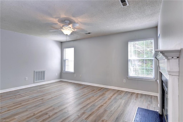 3957 Driftwood Way, Williamsburg, VA 23188 - unfurnished living room featuring plenty of natural light, a ceiling fan, wood finished floors, a premium fireplace, and a textured ceiling